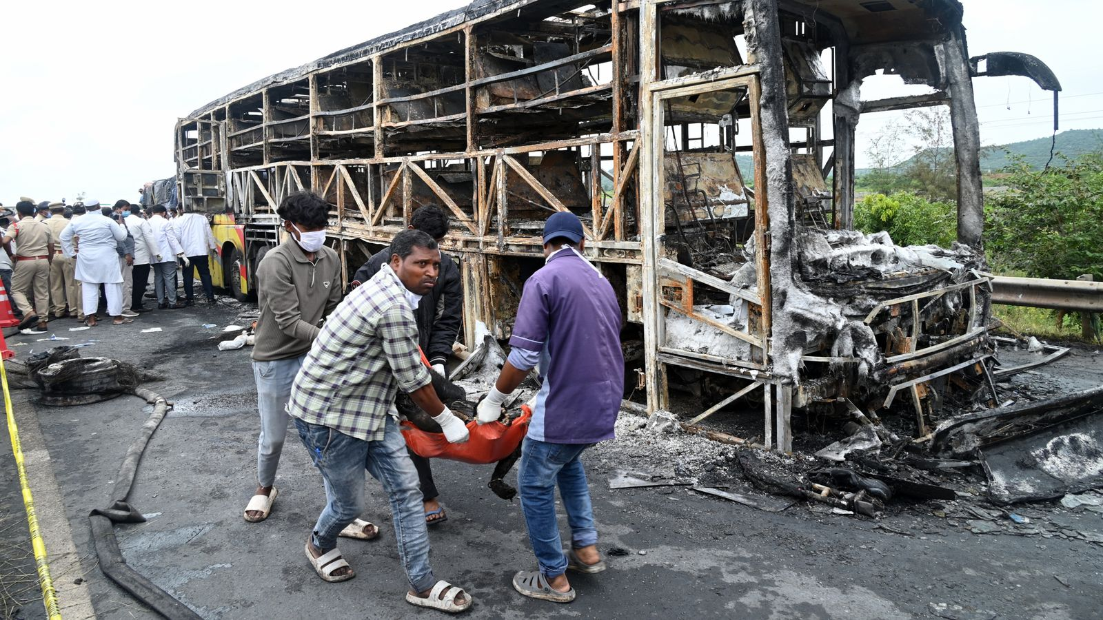 The Bus Burnt Into Ashes And Volunteers Helping To Remove The Remains Of Dead Victims Webp