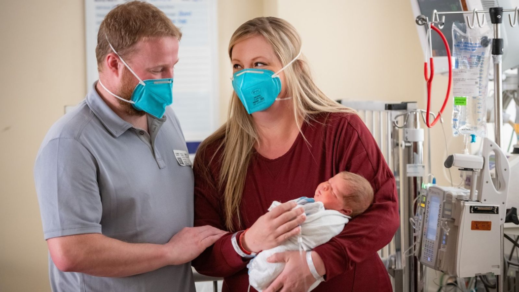 Parents Of The Baby Expressing Delightment As They Hold Onto Their Child Webp